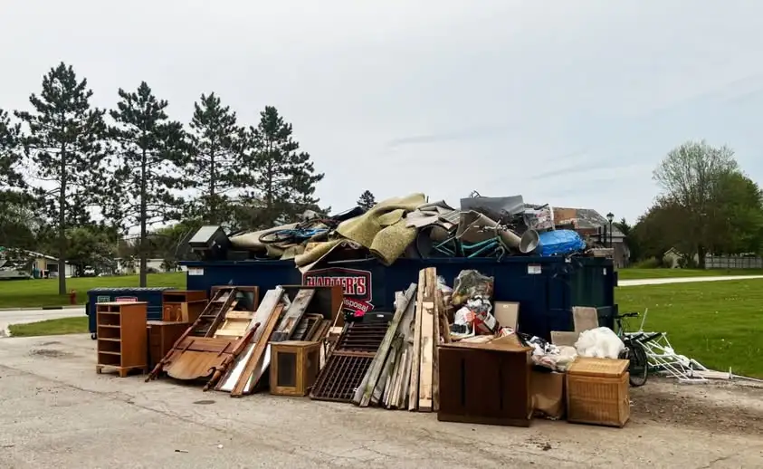 Dumpster filled with furniture, debris, and household junk during a property cleanout