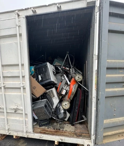 Container filled with old electronics, appliances, and broken equipment for disposal