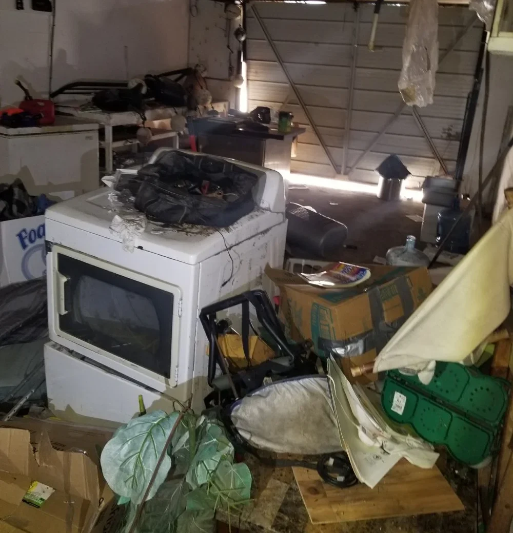 Cluttered garage filled with old appliances, boxes, and household junk before cleanup