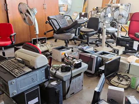Old office furniture and electronic waste stacked for junk removal