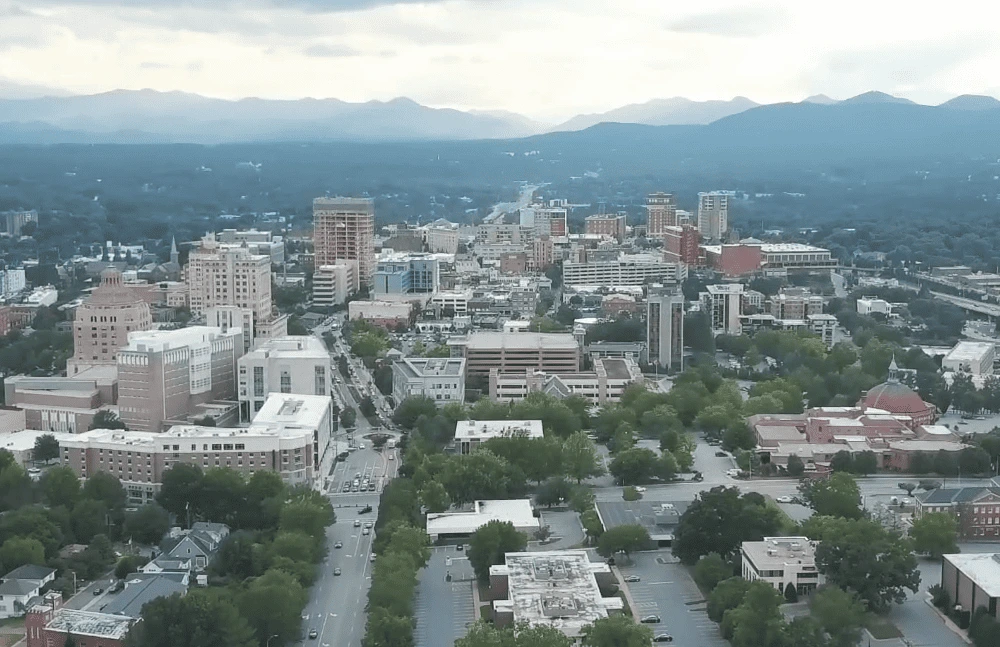 Aerial view of Oakley neighborhood in Asheville, North Carolina with city buildings and mountains in the background.