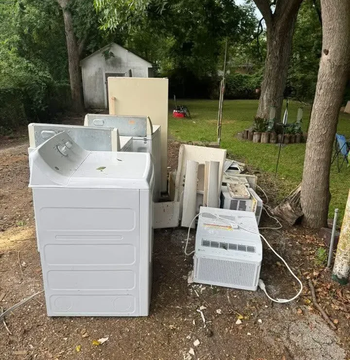 Discarded appliances and electronics in a backyard awaiting junk removal