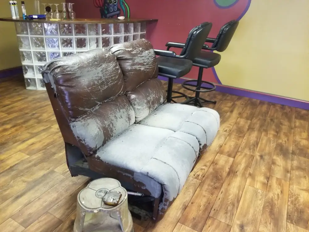 Worn-out leather chair in a room ready for junk removal service