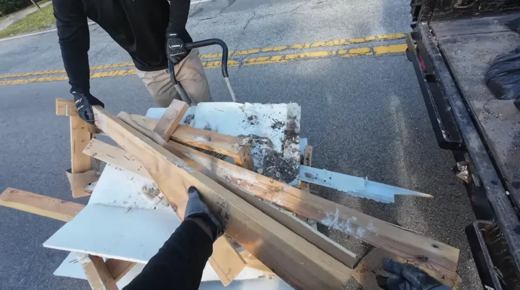 Worker loading wood scraps and demolition materials into a truck.