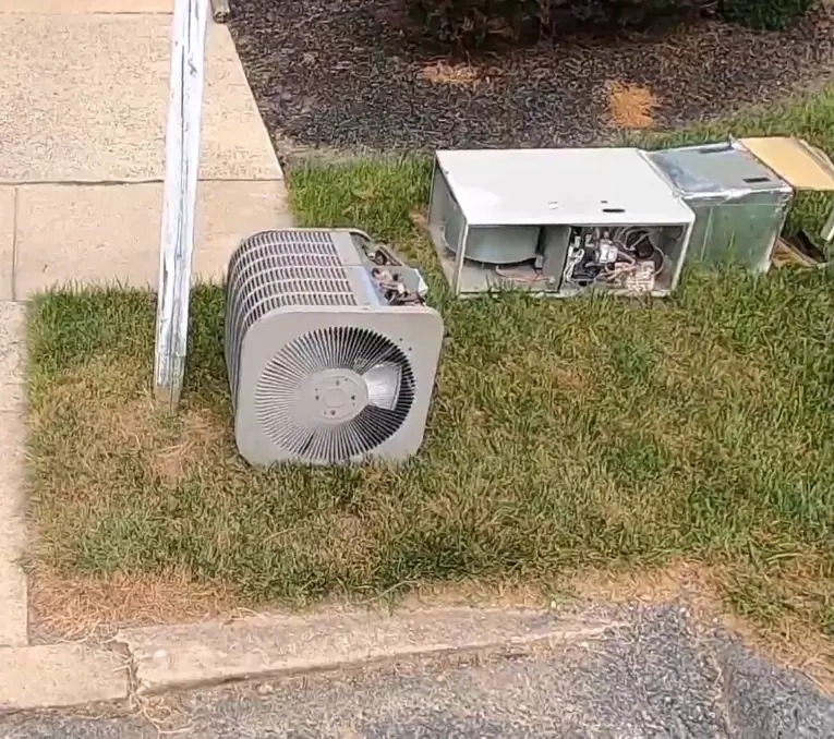 Two old HVAC condenser units sitting on a residential lawn in Asheville NC ready for appliance removal and refrigerant recovery disposal