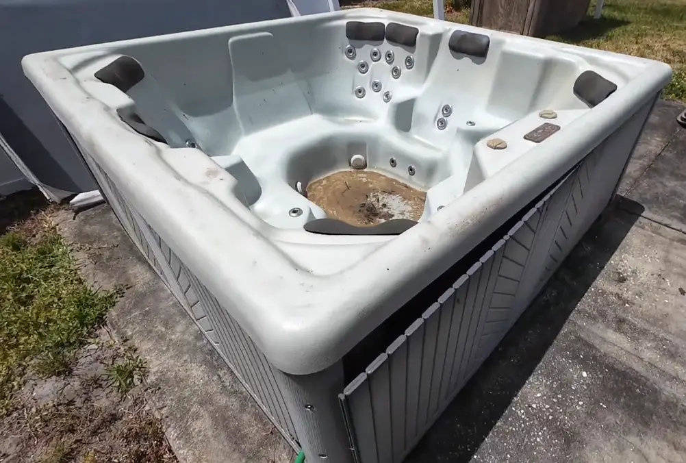 Old weathered hot tub sitting on a concrete pad in a residential backyard in Asheville NC ready for professional hot tub removal and disposal